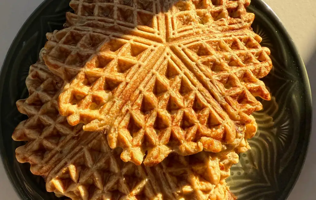Gestapelte herzförmige Protein-Waffeln auf einem grünen Keramikteller im Morgenlicht